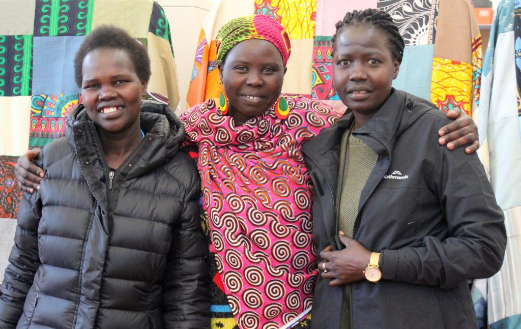 Three women smiling in colourful fabrics.