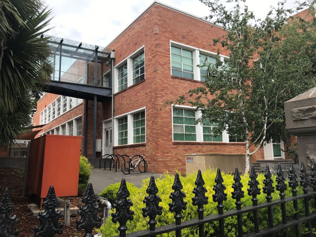 Red brick building with glass walkway, daytime