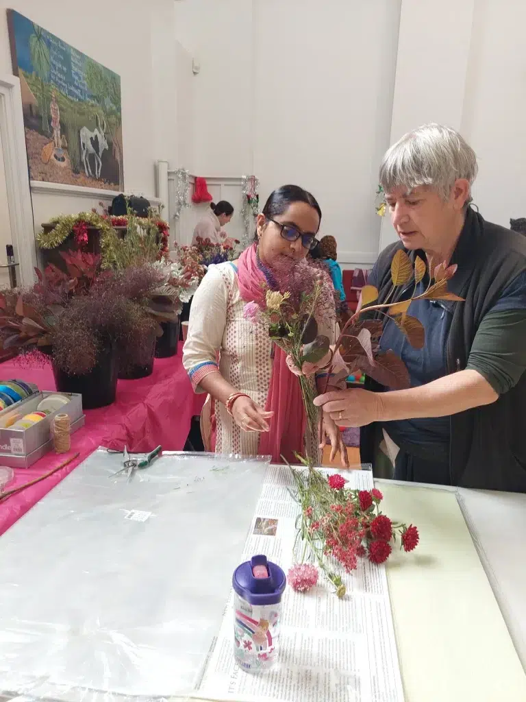 Two people arranging flowers creatively in workshop.