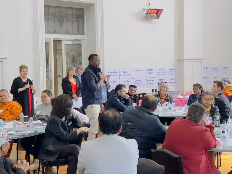 Community meeting with diverse participants speaking.