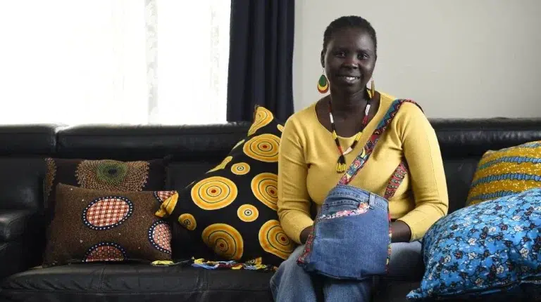 Woman with colourful pillows on couch, smiling.