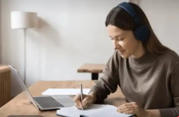 Woman studying with headphones and laptop.