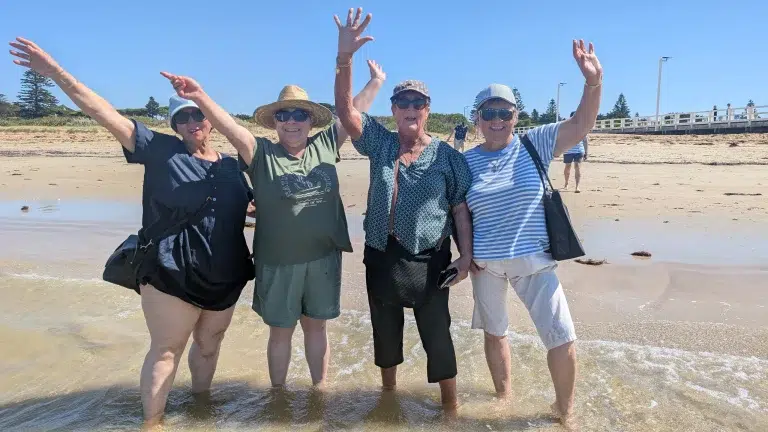 Four friends smiling on sunny beach