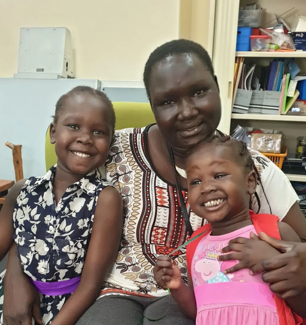 Smiling family with green balloon indoors.