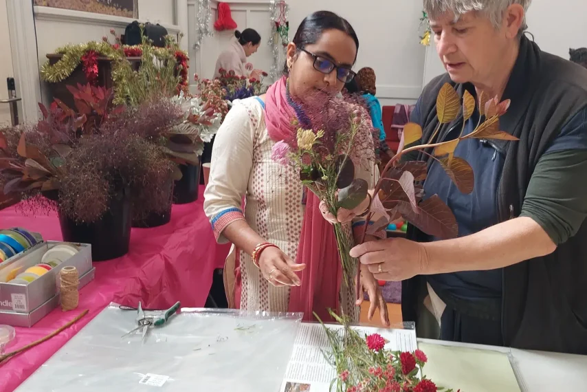 Two people arranging flowers creatively in workshop.