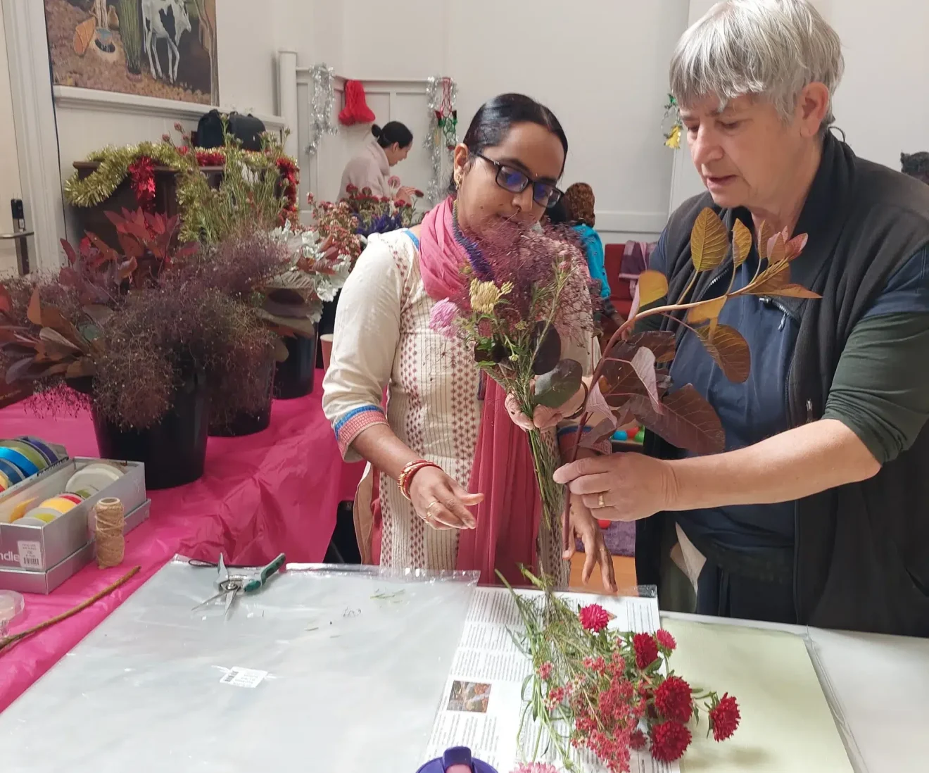 Two people arranging flowers creatively in workshop.