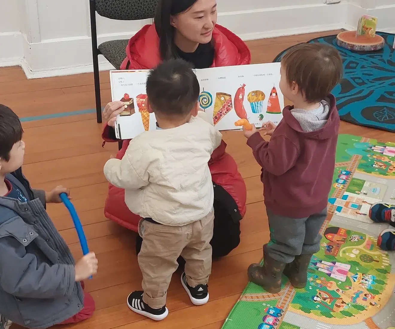Storytime with teacher and kids on colourful mat.