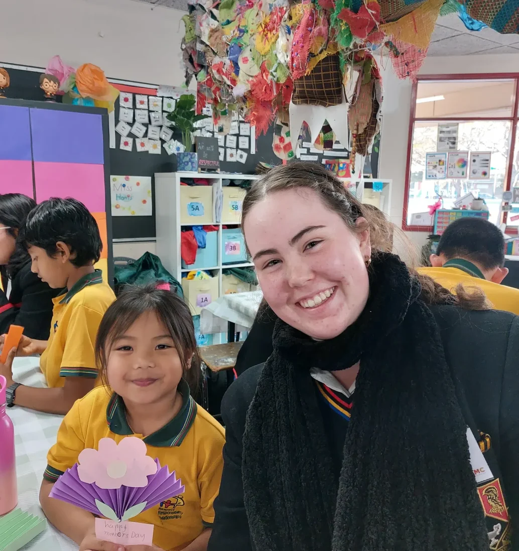 Teacher and student crafting in a colourful classroom.
