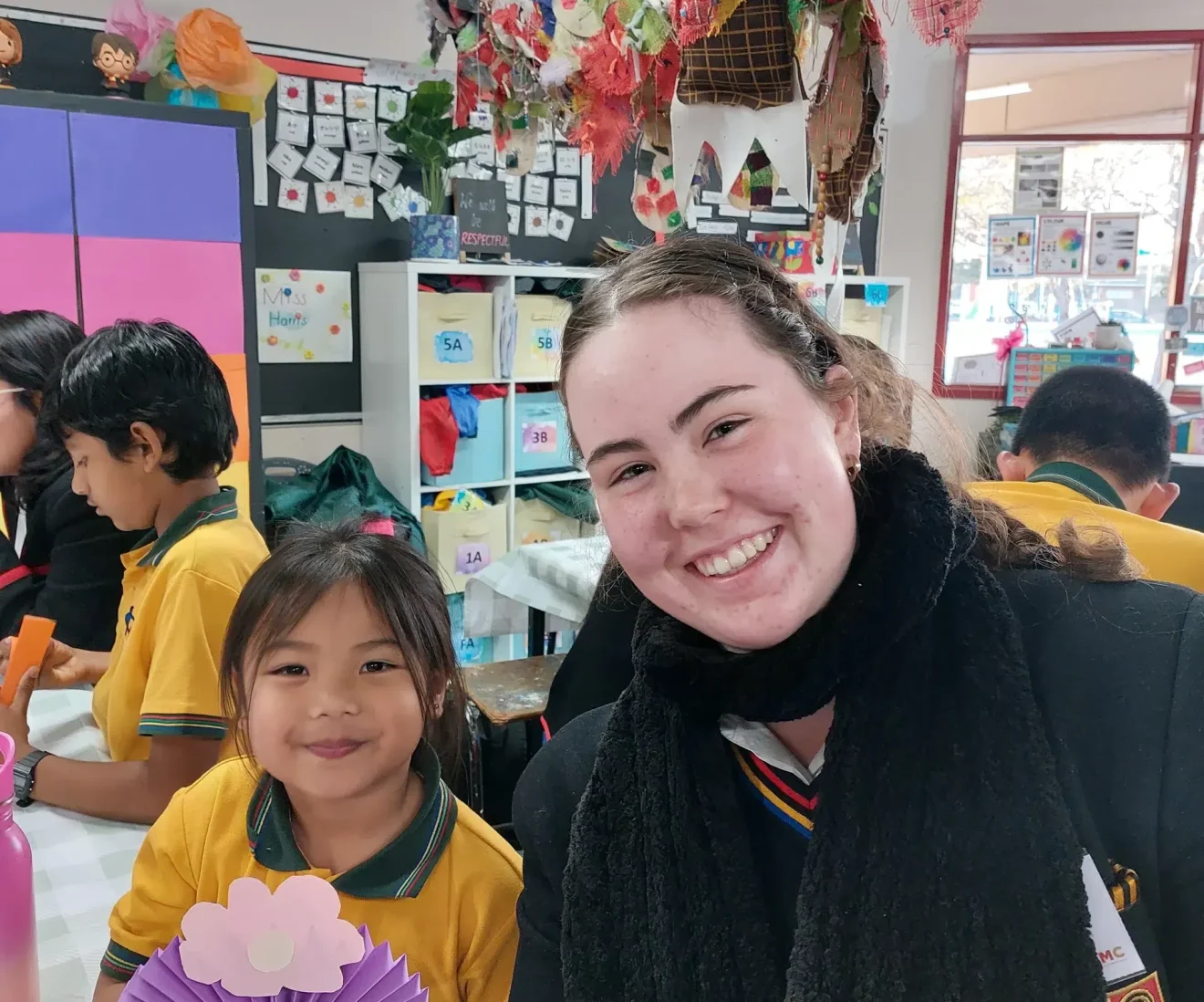 Teacher and student crafting in a colourful classroom.