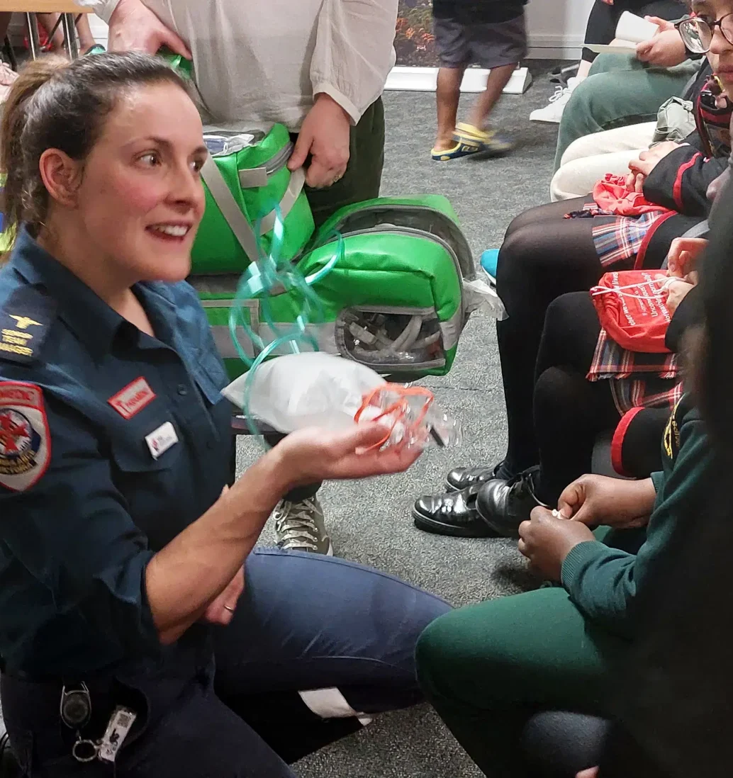 Paramedic demonstrating CPR equipment to students.