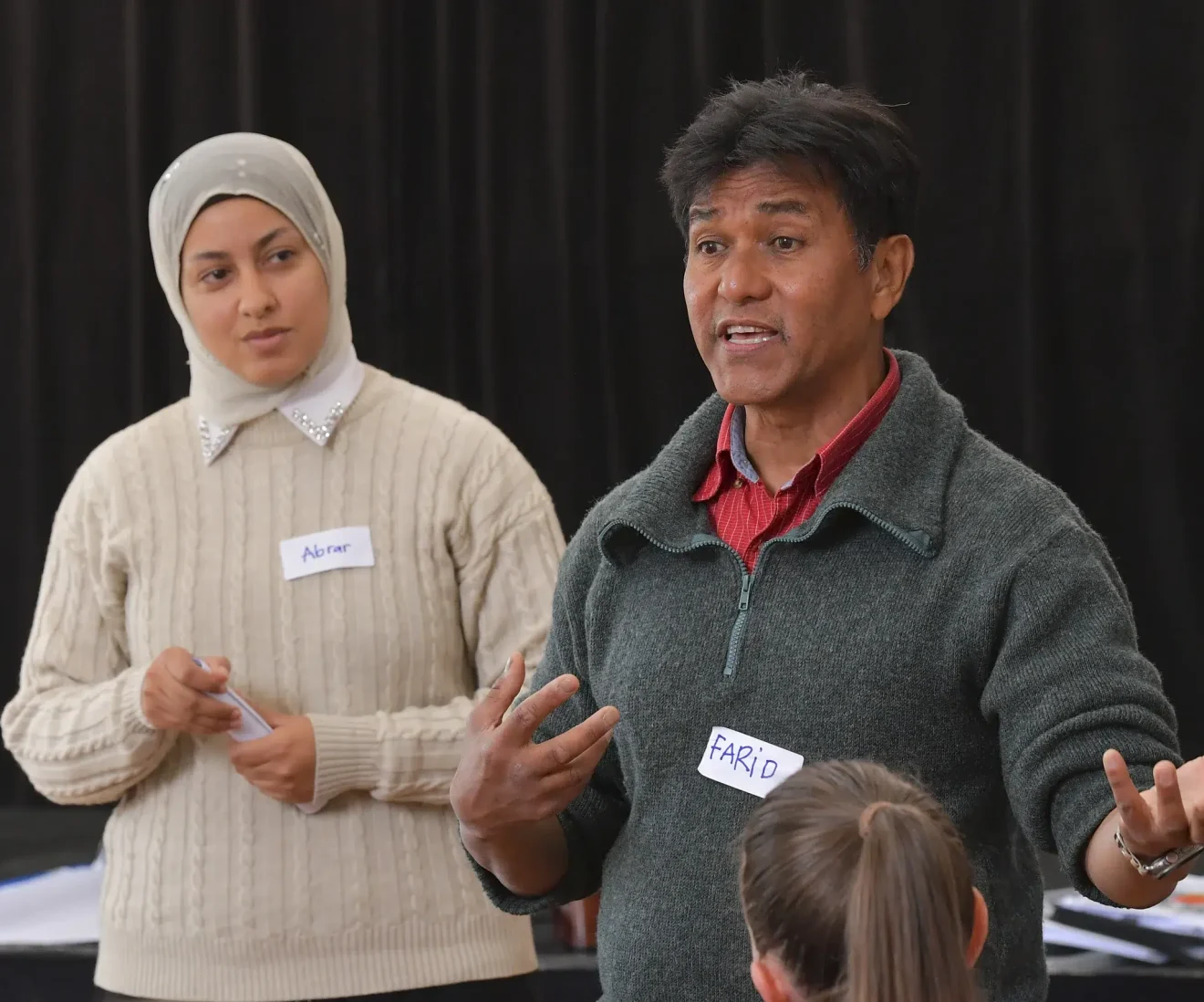 Two people speaking to a group indoors.