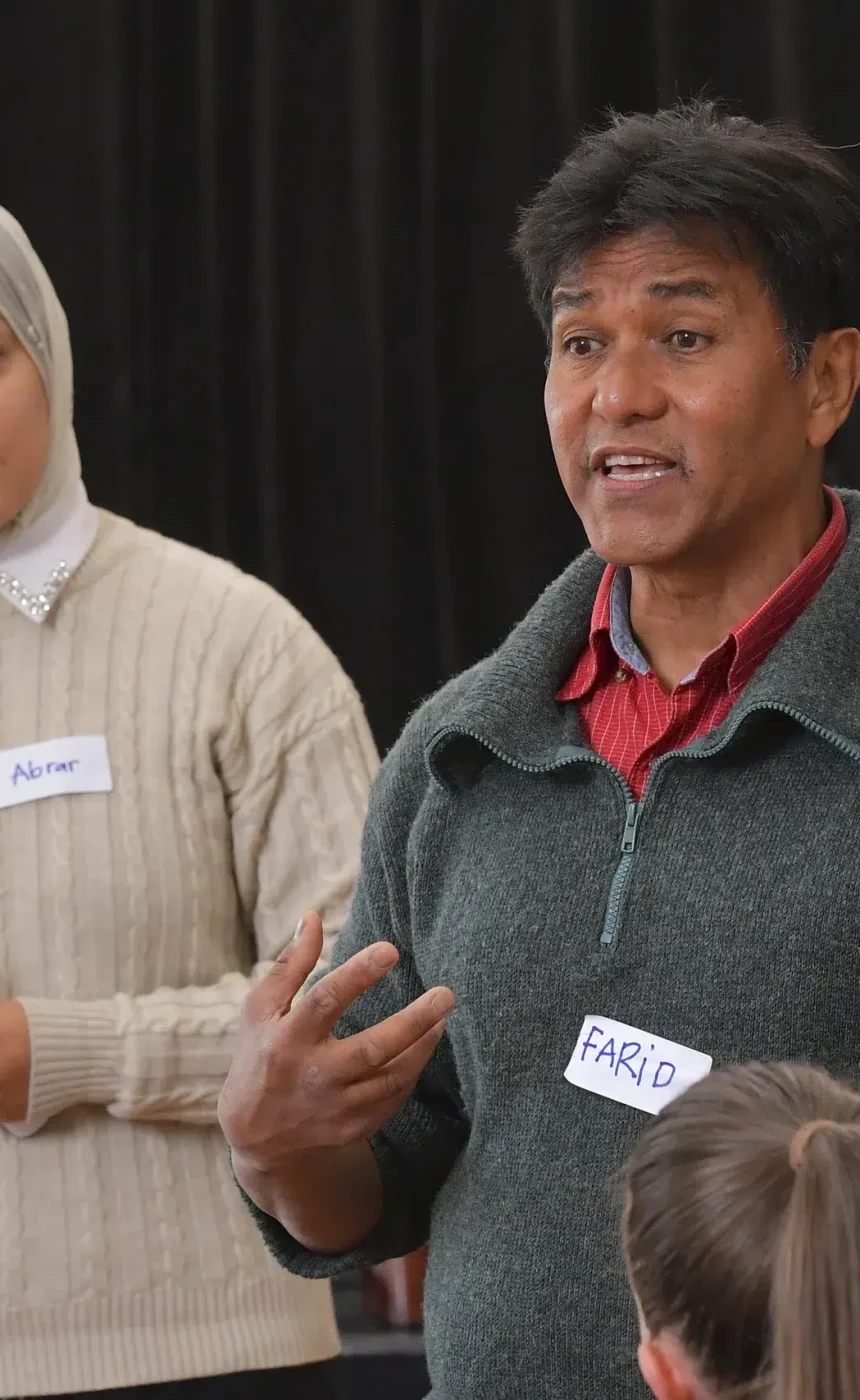 Two people speaking to a group indoors.