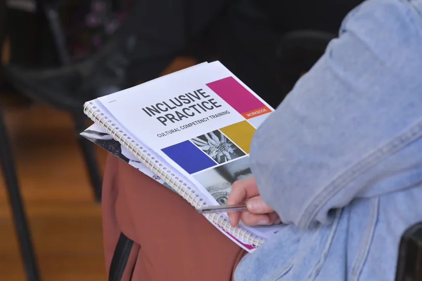 Person holding inclusive practice training workbook.