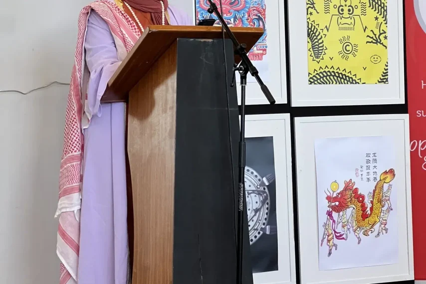 Woman in colourful attire speaks at podium.