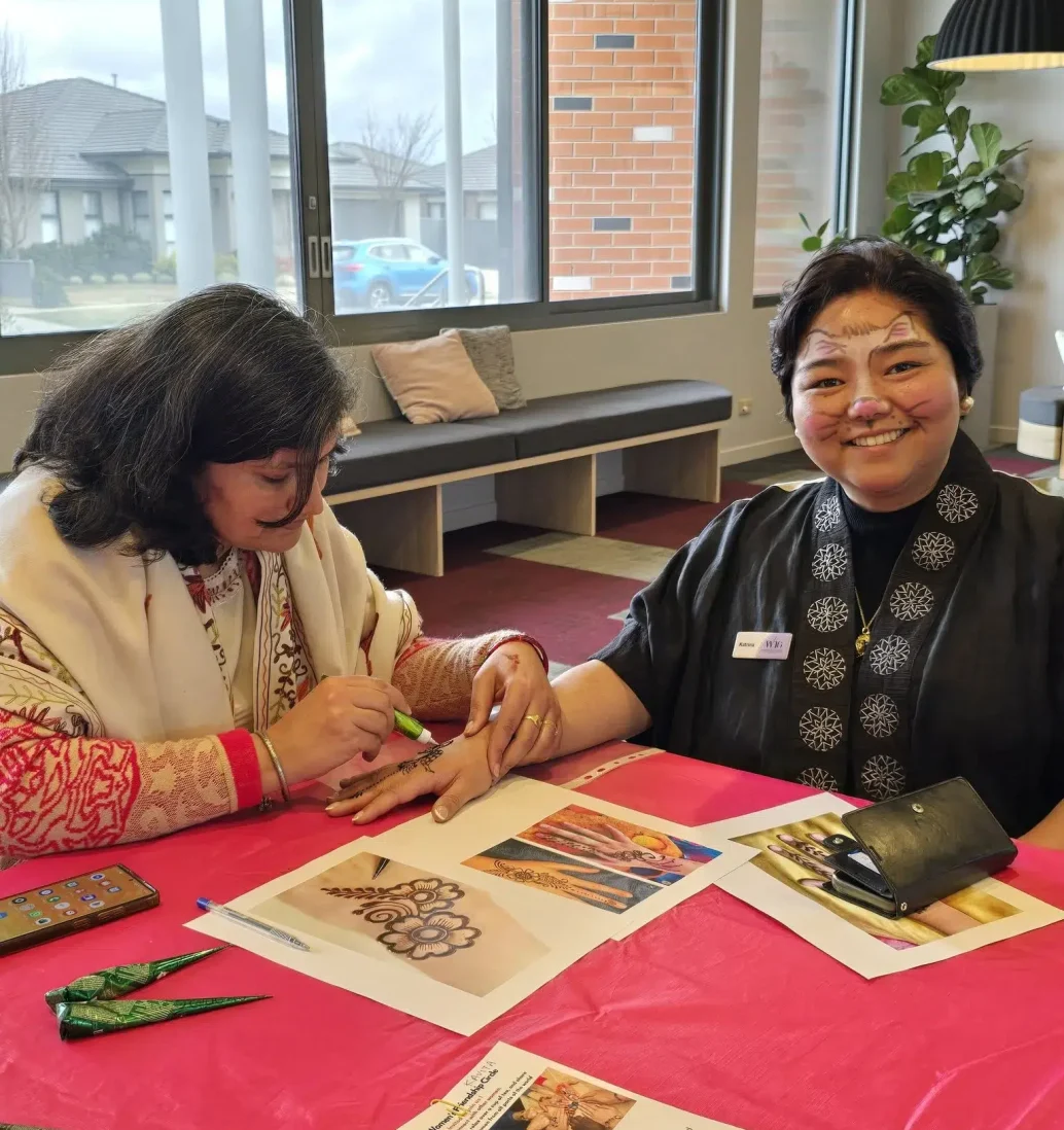 Woman applying henna in community centre.
