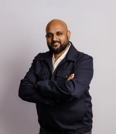 Man in navy jacket smiling, arms crossed