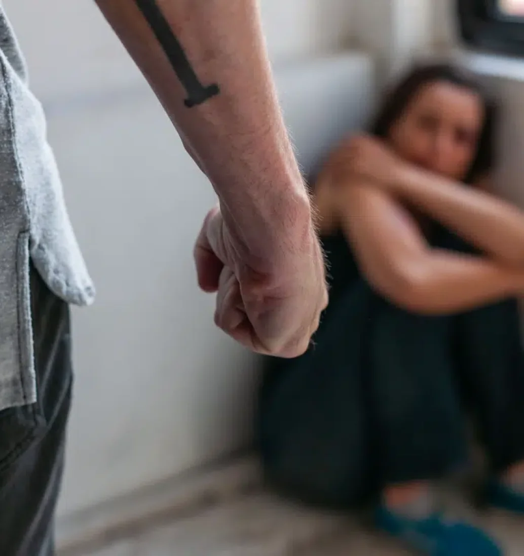 Close-up of threatening fist, person in background fearful.