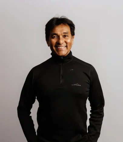 Smiling person in black jacket against plain background