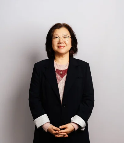 Smiling person in glasses and black coat.