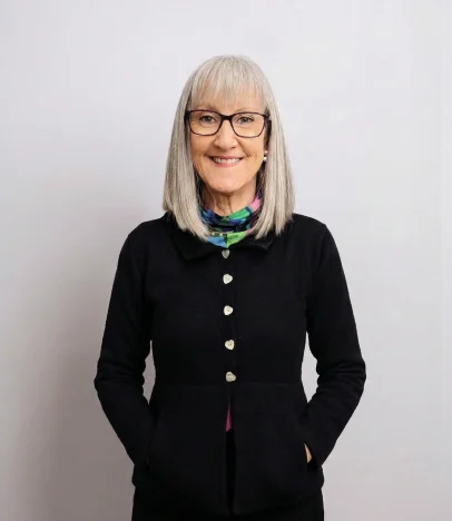 Woman with grey hair and glasses smiling.