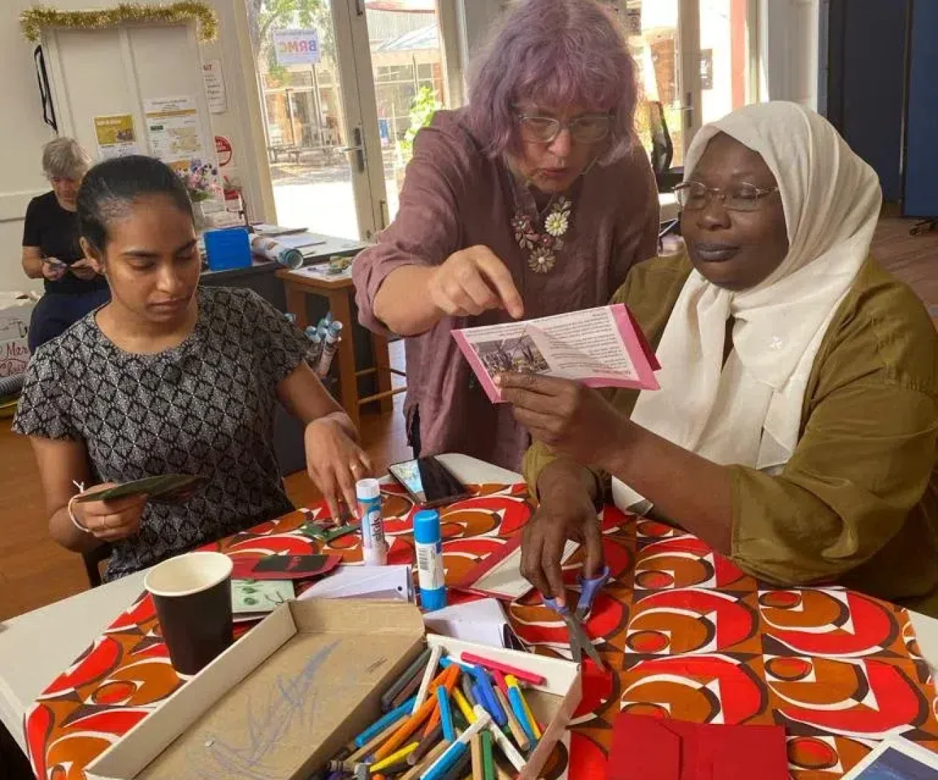 Women crafting together at a table with supplies.