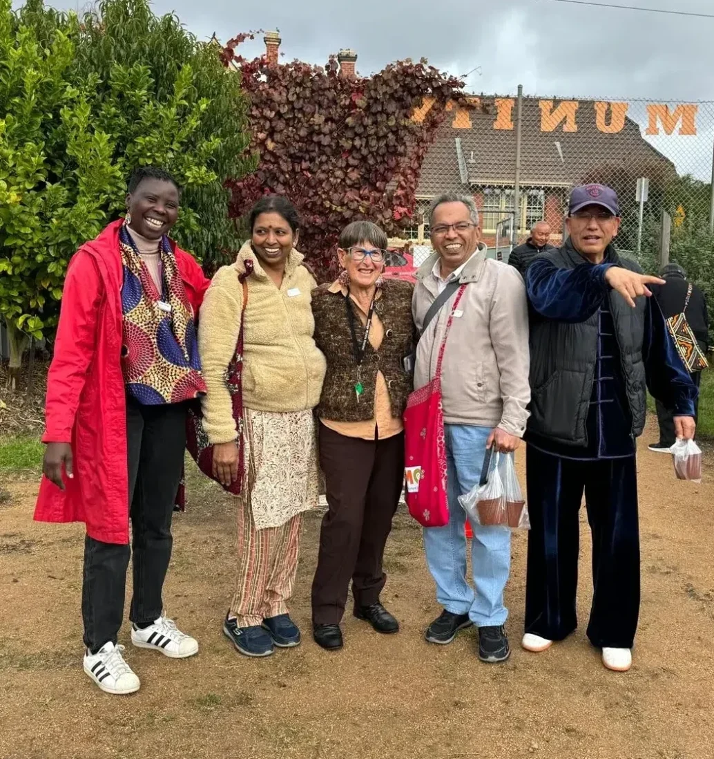 Group smiling in community garden setting.