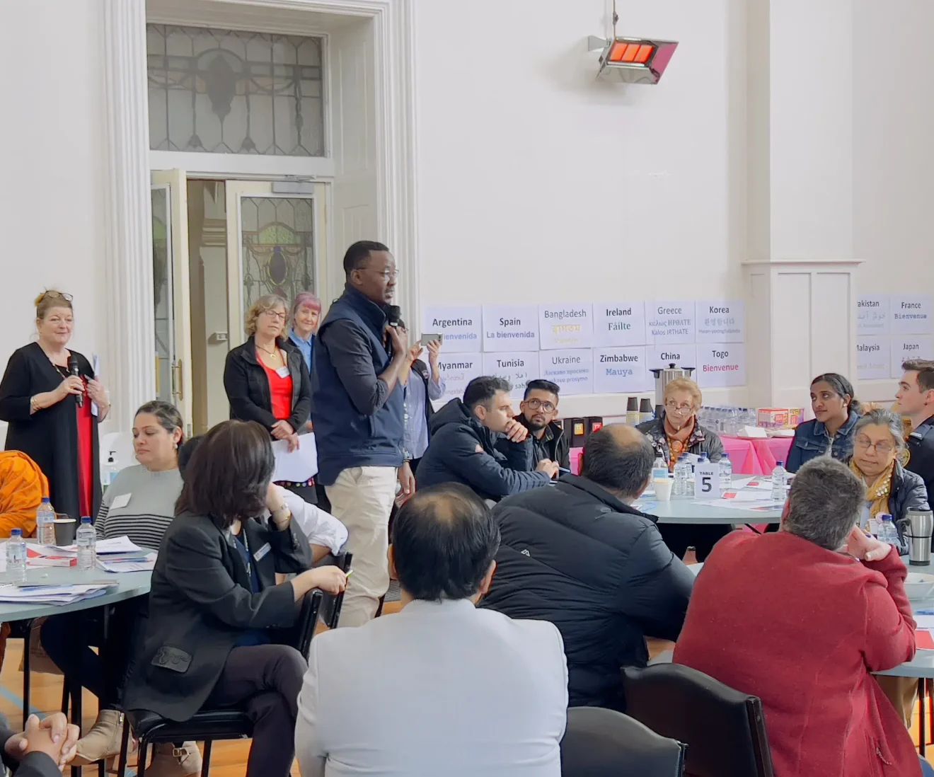 Community meeting with diverse participants speaking.