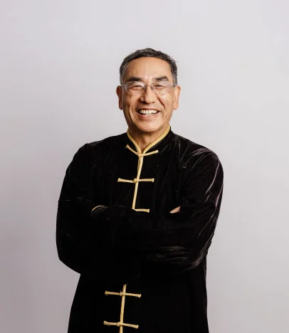 Smiling man in traditional attire with glasses.