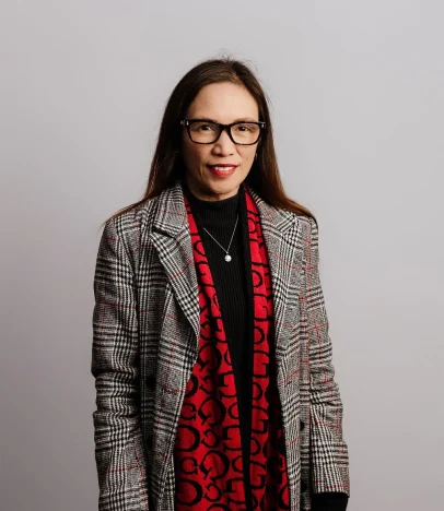 Woman in glasses with red scarf and plaid coat.