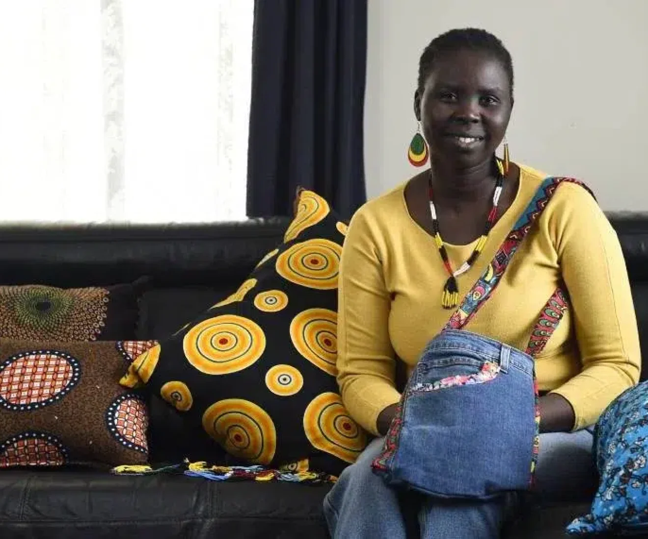 Woman with colourful pillows on couch, smiling.