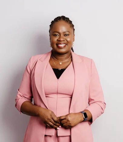 Smiling person in pink suit, standing confidently.