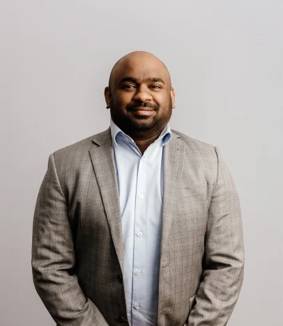Man in grey checked suit smiling at camera