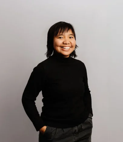 Person smiling in black sweater and trousers.