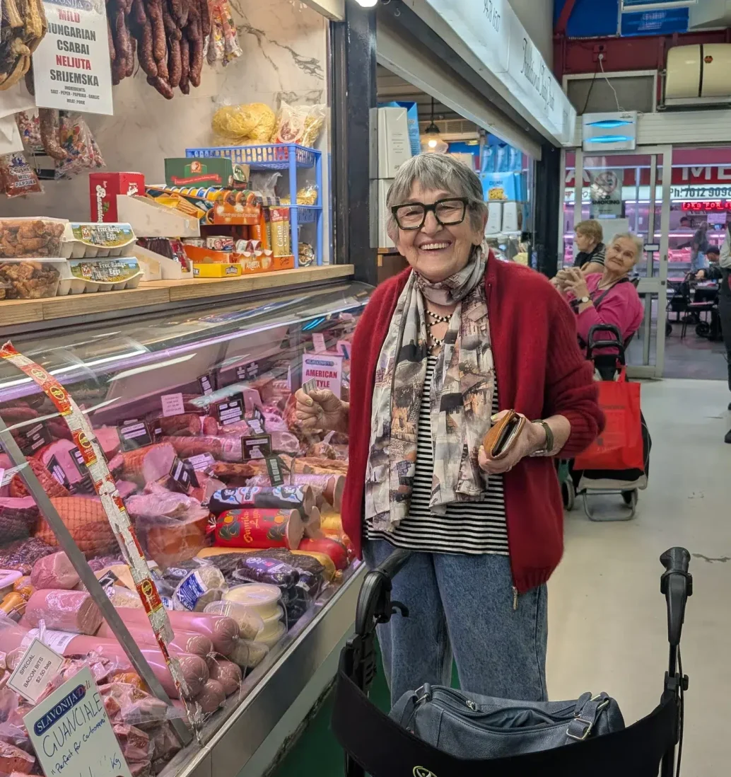 Smiling woman shopping at a deli counter.