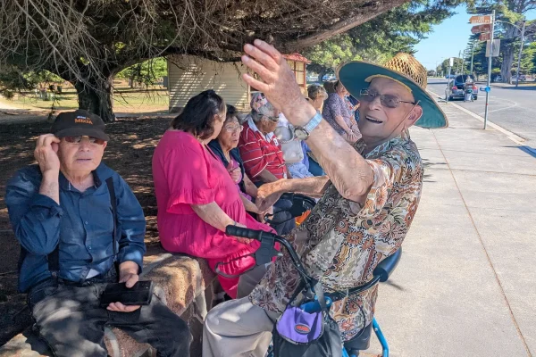 Elderly group sitting outdoors enjoying sunny day.