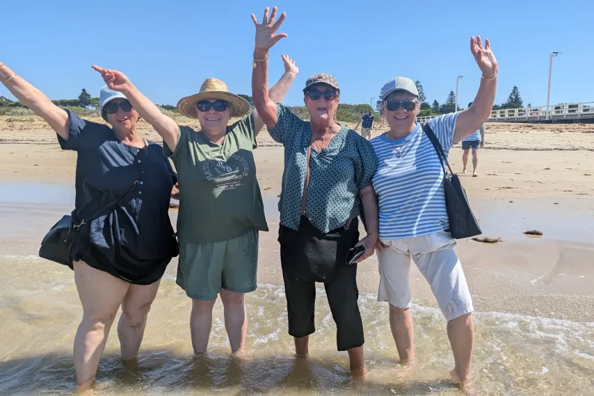 Four friends smiling on sunny beach