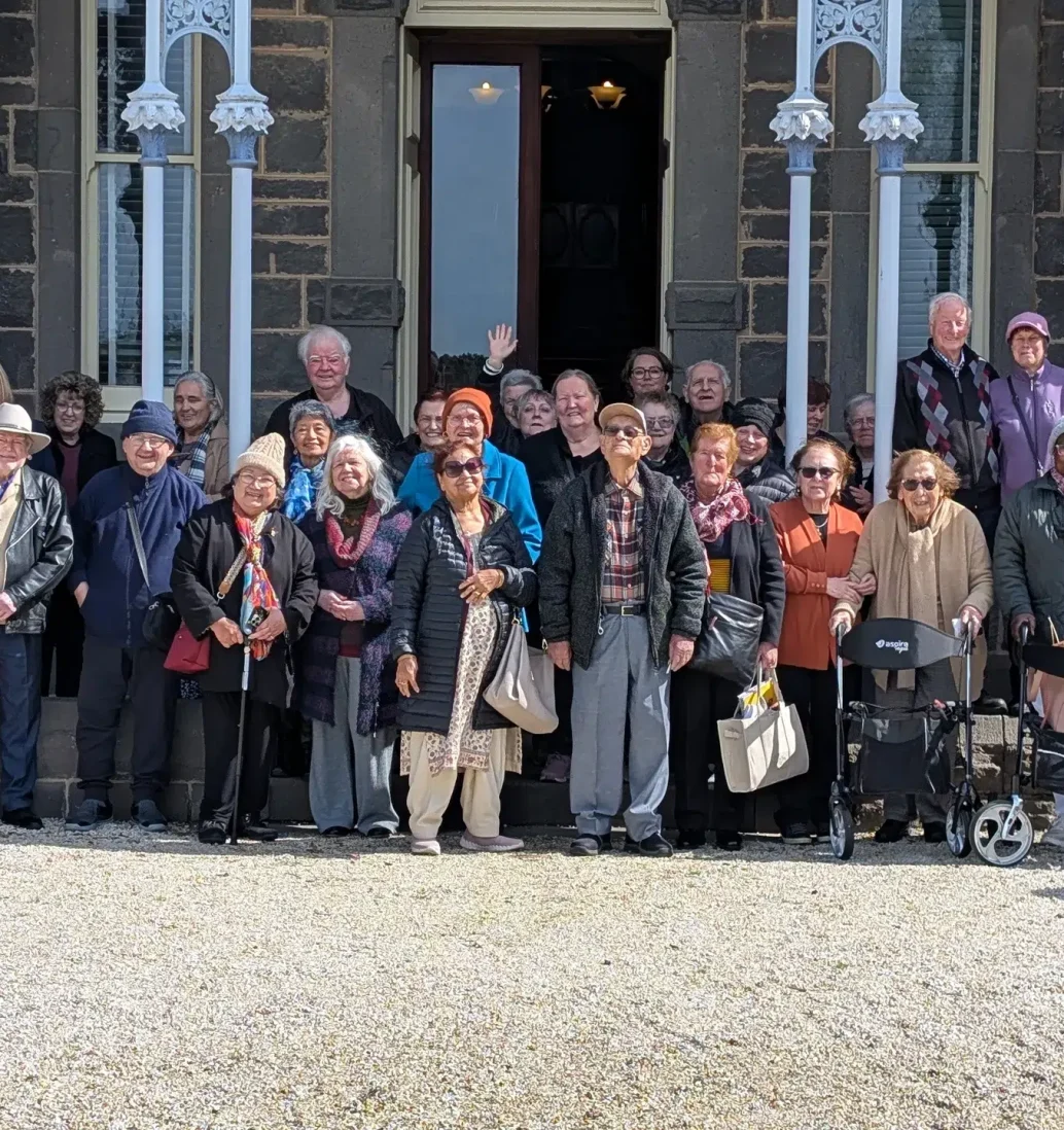 Group of people posing outside a historic building.